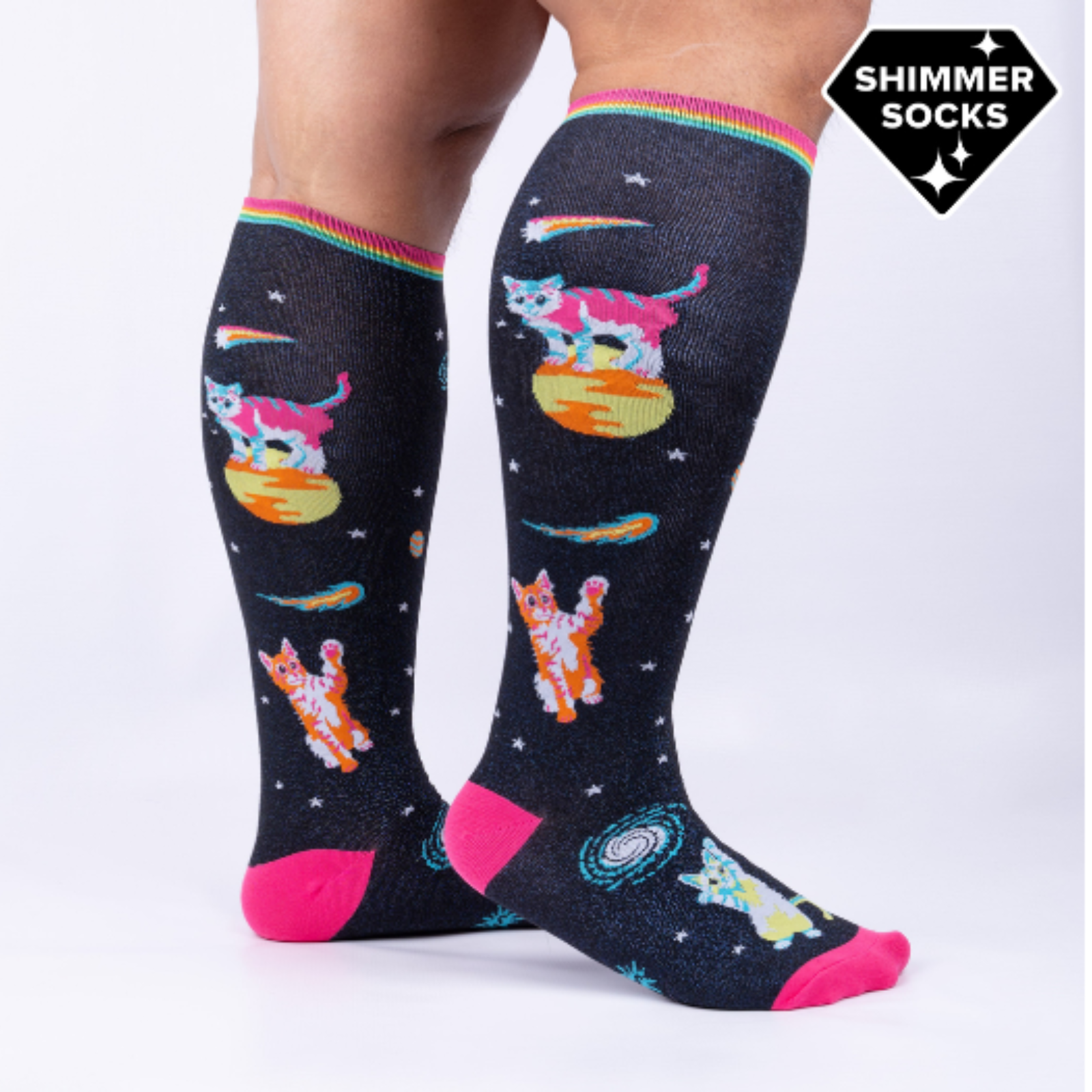 Sock It To Me Space Cats extra-stretchy knee sock featuring pink toe and heel with shimmery black background and kittens in outer space. Socks worn by model seen from side. 