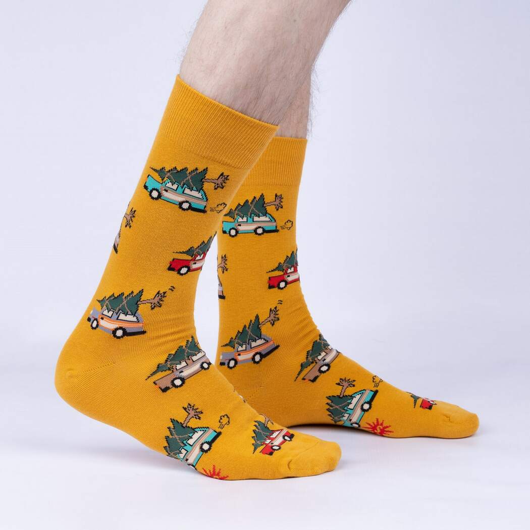 Sock It To Me Little Full, Lotta Sap men's crew sock featuring mustard yellow sock with images of station wagons with christmas trees tied to the top. Socks shown on model's feet from the side. 