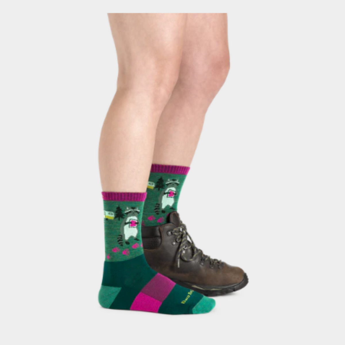 Darn Tough 5001 Critter Club Micro Crew Lightweight Hiking Women&#39;s Sock featuring green sock with purple cuff and raccoon holding jam sandwich. Sock shown on model wearing one boot. 