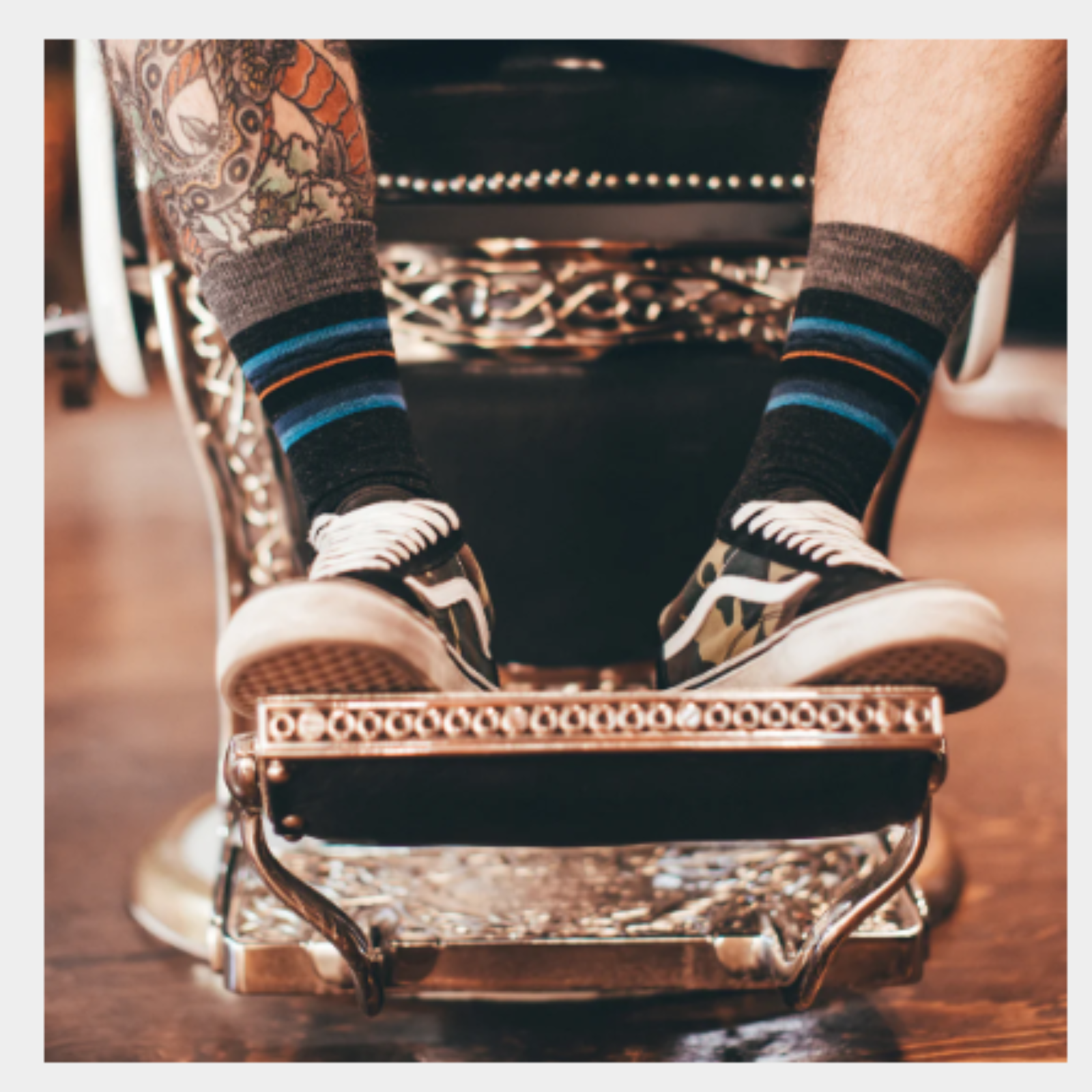 Darn Tough 6009 Whetstone Crew Lightweight men's crew sock featuring charcoal grey sock with blue, red, and black stripes at the top. Sock shown on model's feet. 