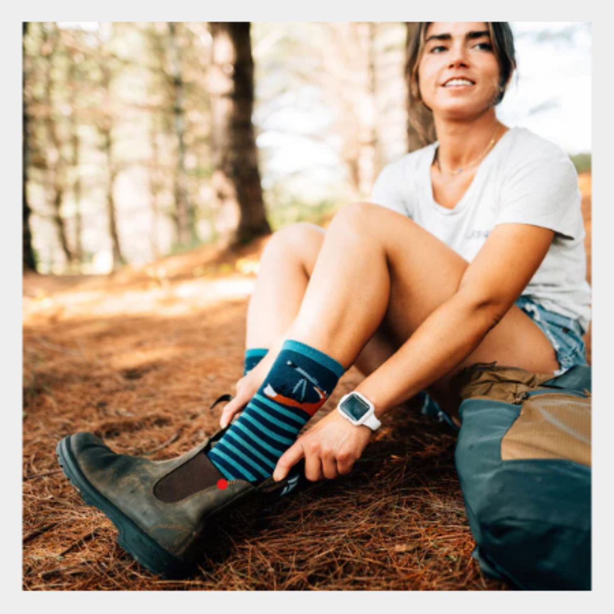 Darn Tough 6037 Animal Haus Lightweight Cushion Crew women&#39;s sock featuring navy blue sock with teal stripes and stars at top. Sock shown on model in the woods.. 