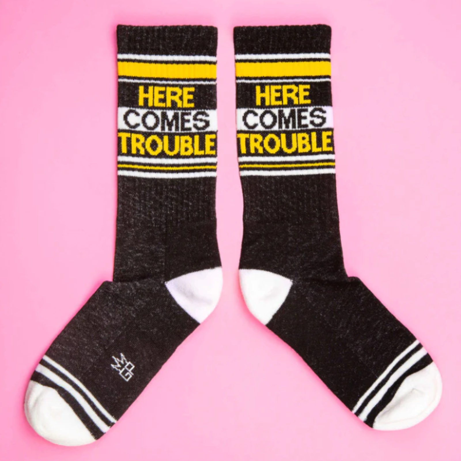 Gumball Poodle Here Comes Trouble women's and men's sock featuring black sock with white and yellow "here comes trouble" in capital letters on display 