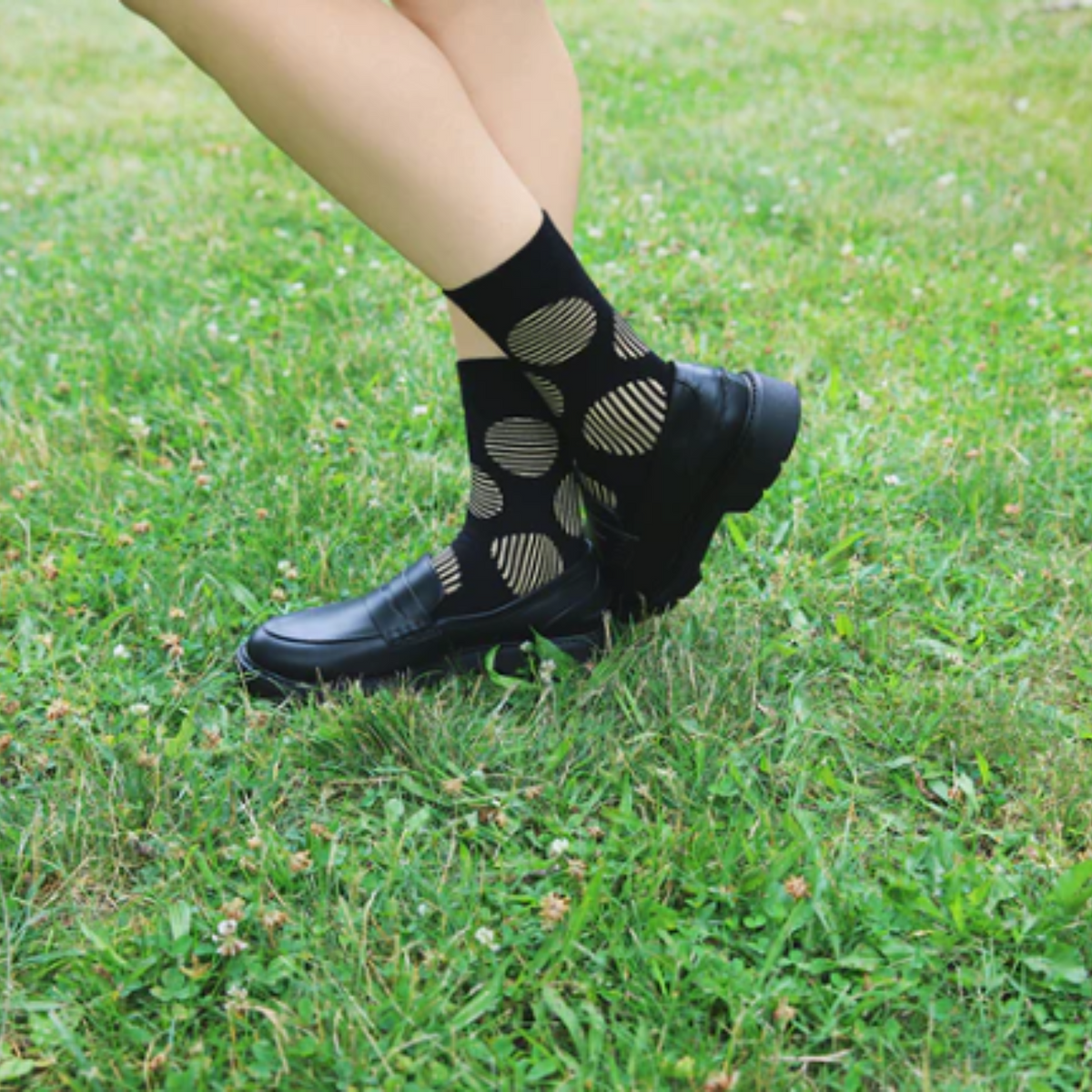MeMoi Retro Circle women&#39;s Crew sock featuring black sock with brown stripes in circle patterns all over. Socks shown on model in grass.