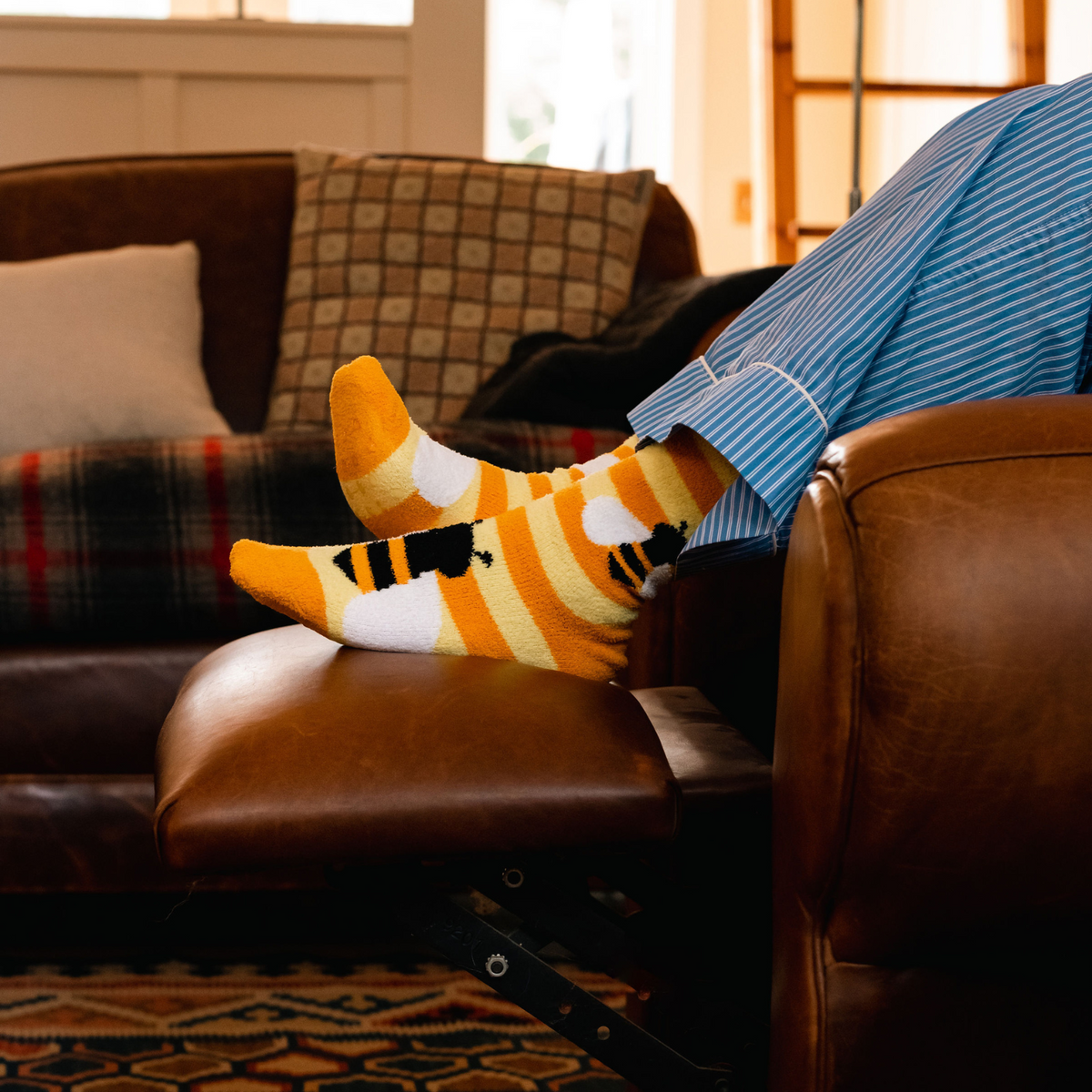 Sock It To Me Bee Cozy women&#39;s yellow stripe slipper sock featuring bees all over on model in chair