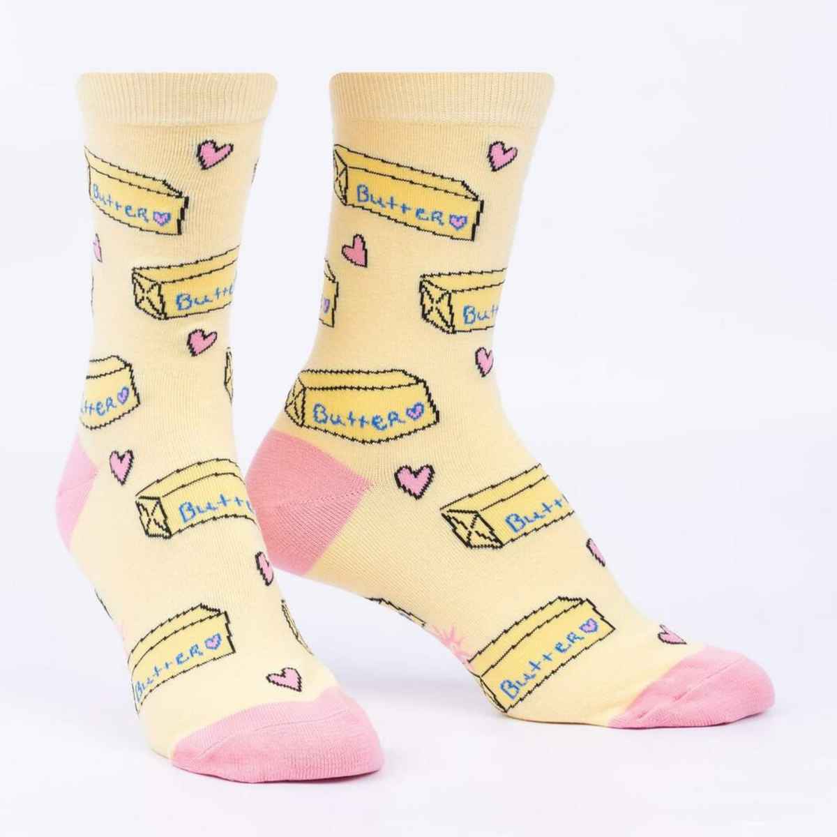 Sock It To Me Butter Me Up women&#39;s yellow crew sock featuring pink hearts, heel and toe with sticks of butter all over on display feet