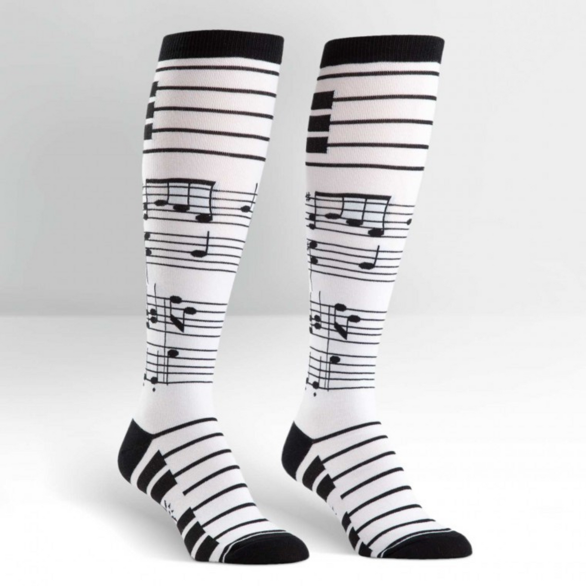 Sock it to Me Foot Notes women&#39;s knee high sock featuring white sock with black musical notes all over on display feet