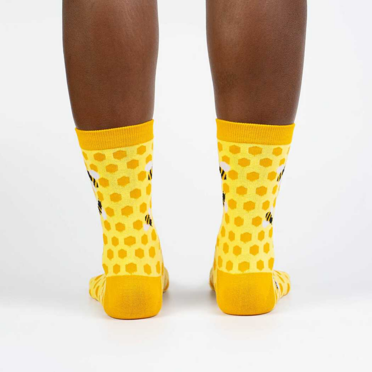 Sock It To Me women&#39;s yellow sock Bees Knees featuring honeycomb and bees all over on model from behind