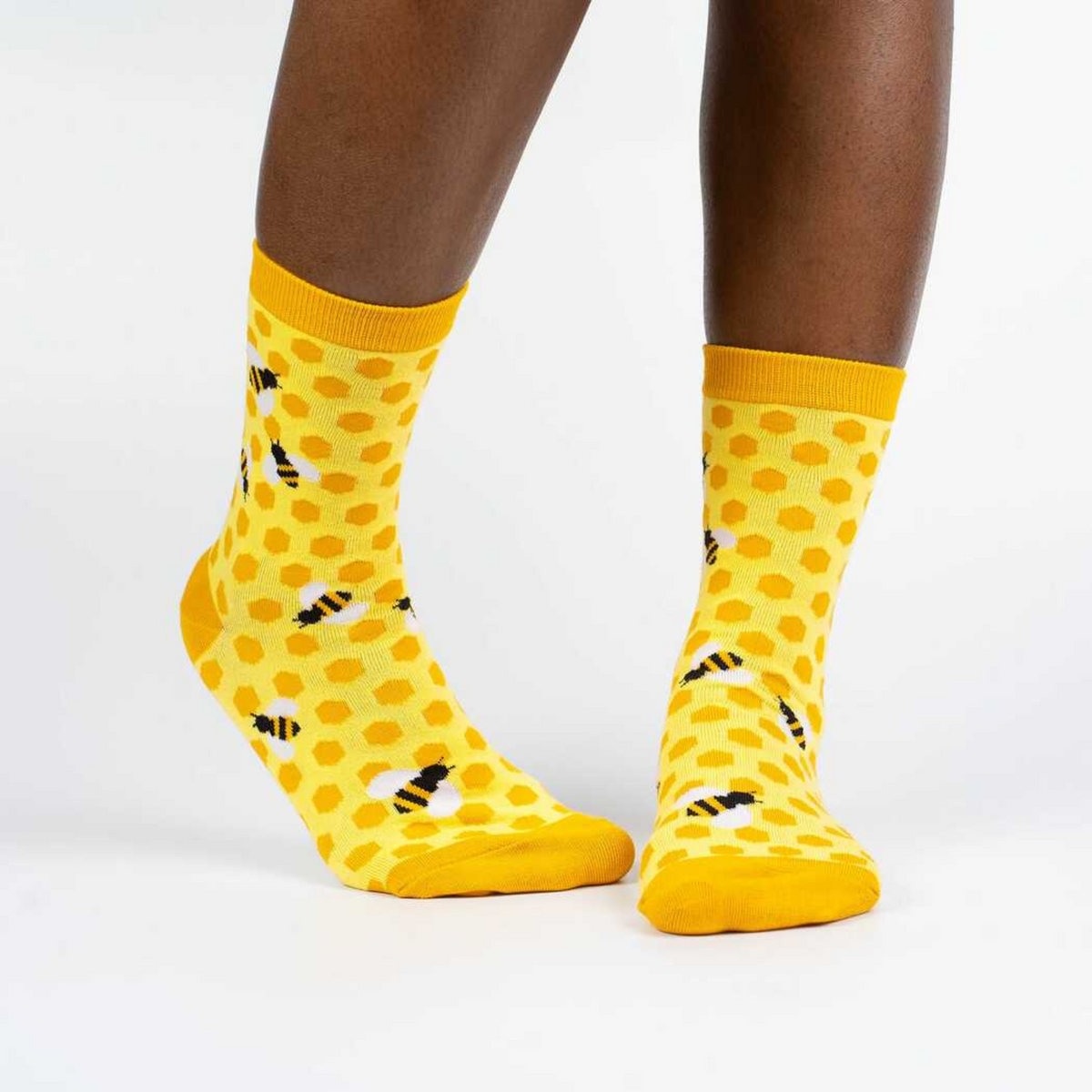 Sock It To Me women&#39;s yellow sock Bees Knees featuring honeycomb and bees all over on model from front