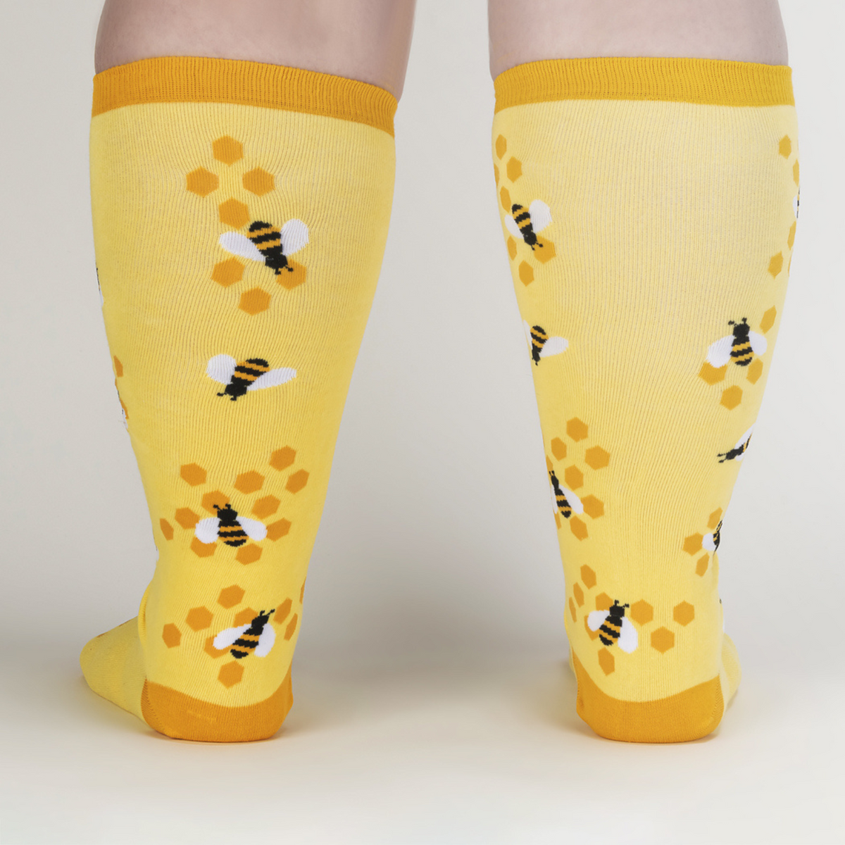 Sock It To Me extra-stretchy yellow knee high sock Bees Knees featuring honeycomb and bees all over on model from behind