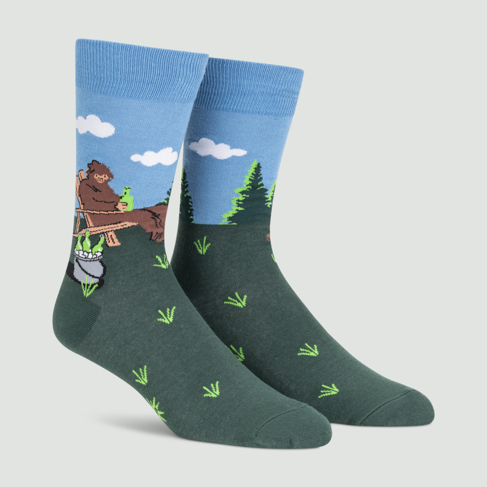 Sock It To Me Bucket List men's crew sock featuring Sasquatch sitting on a lawn in a chair drinking beer with a bucket of beer shown on display feet