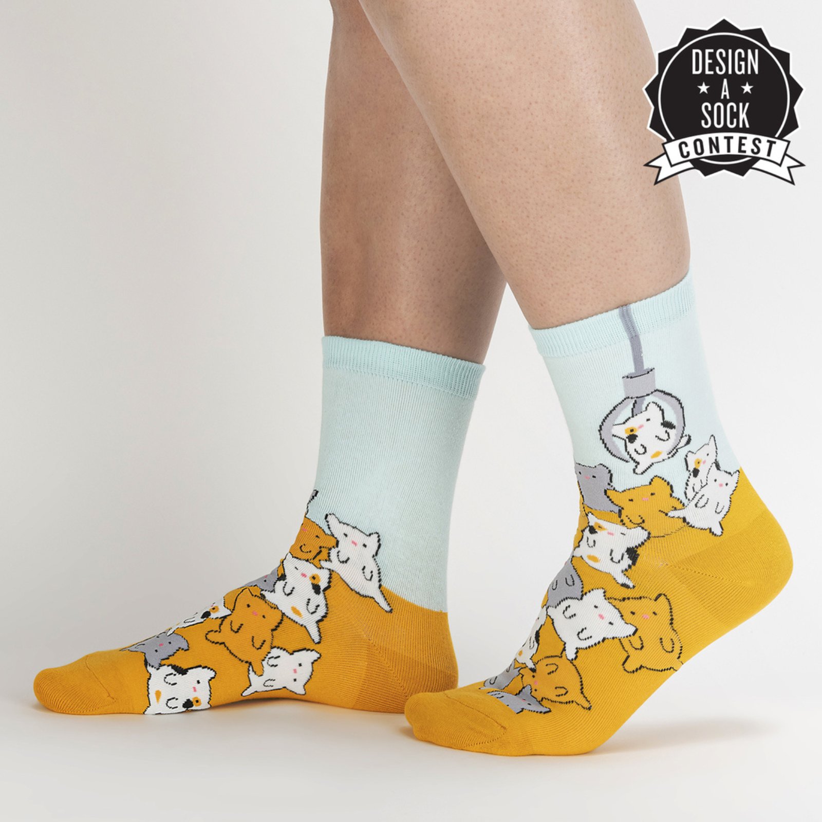Sock It To Me Cat Claw women's sock featuring light blue and yellow sock with claw prize machine catching a cat as worn by model seen from side