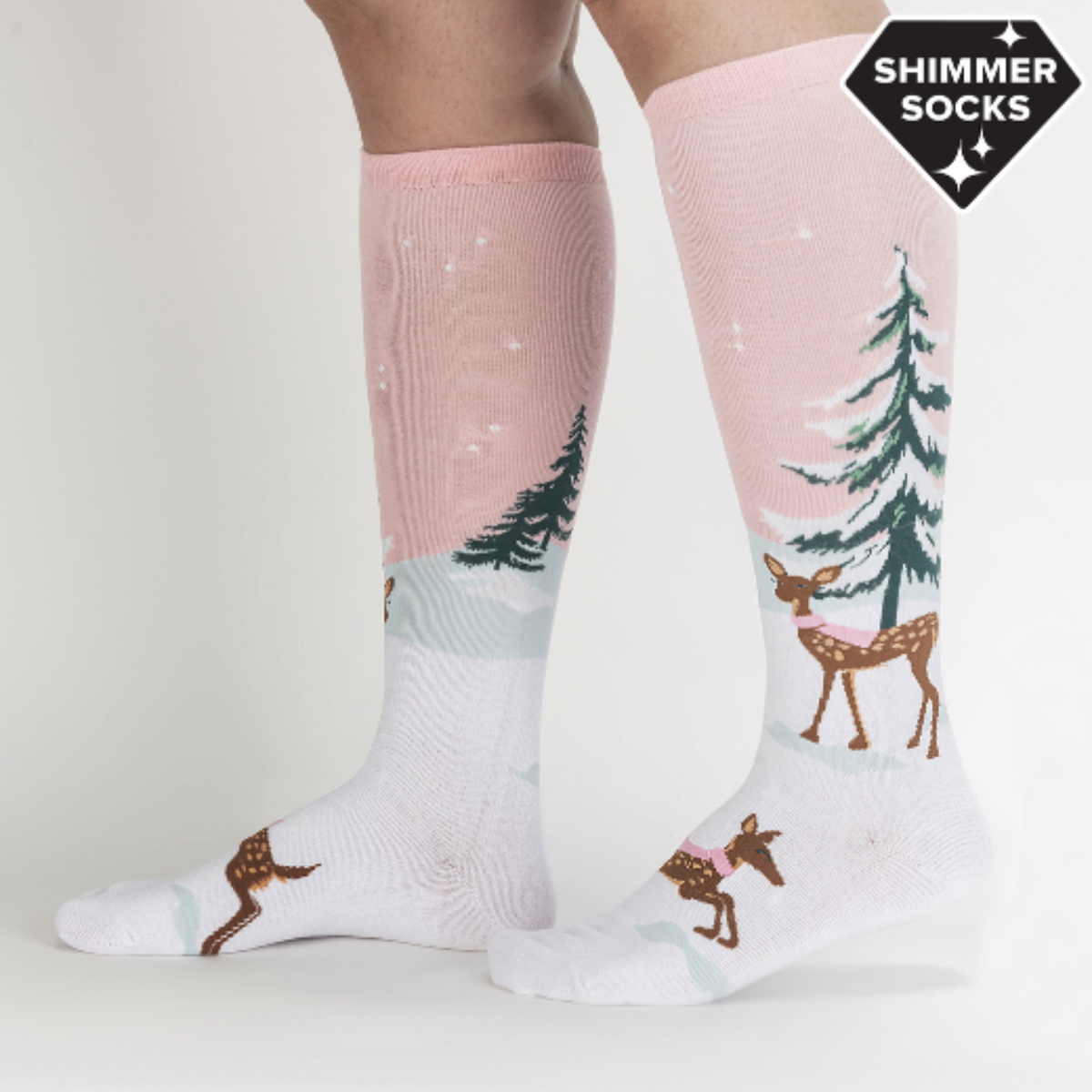 Sock It To Me Doe-nt Forget Your Scarf women&#39;s knee high sock featuring pink sock with snow-covered fir tree and deer with pink scarf. Socks worn by model seen from side. 