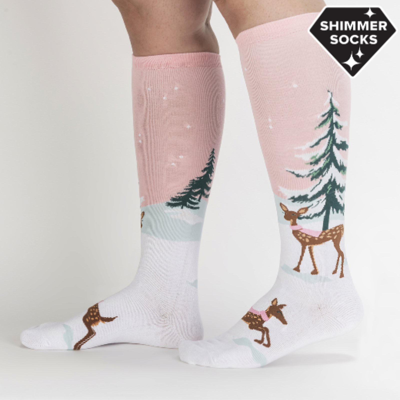 Sock It To Me Doe-nt Forget Your Scarf women's knee high sock featuring pink sock with snow-covered fir tree and deer with pink scarf. Socks worn by model seen from side. 
