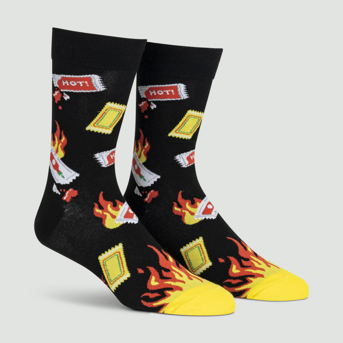 Sock It To Me Extra Hot men&#39;s sock featuring black crew sock with hot sauce packets and flames at toes on display feet