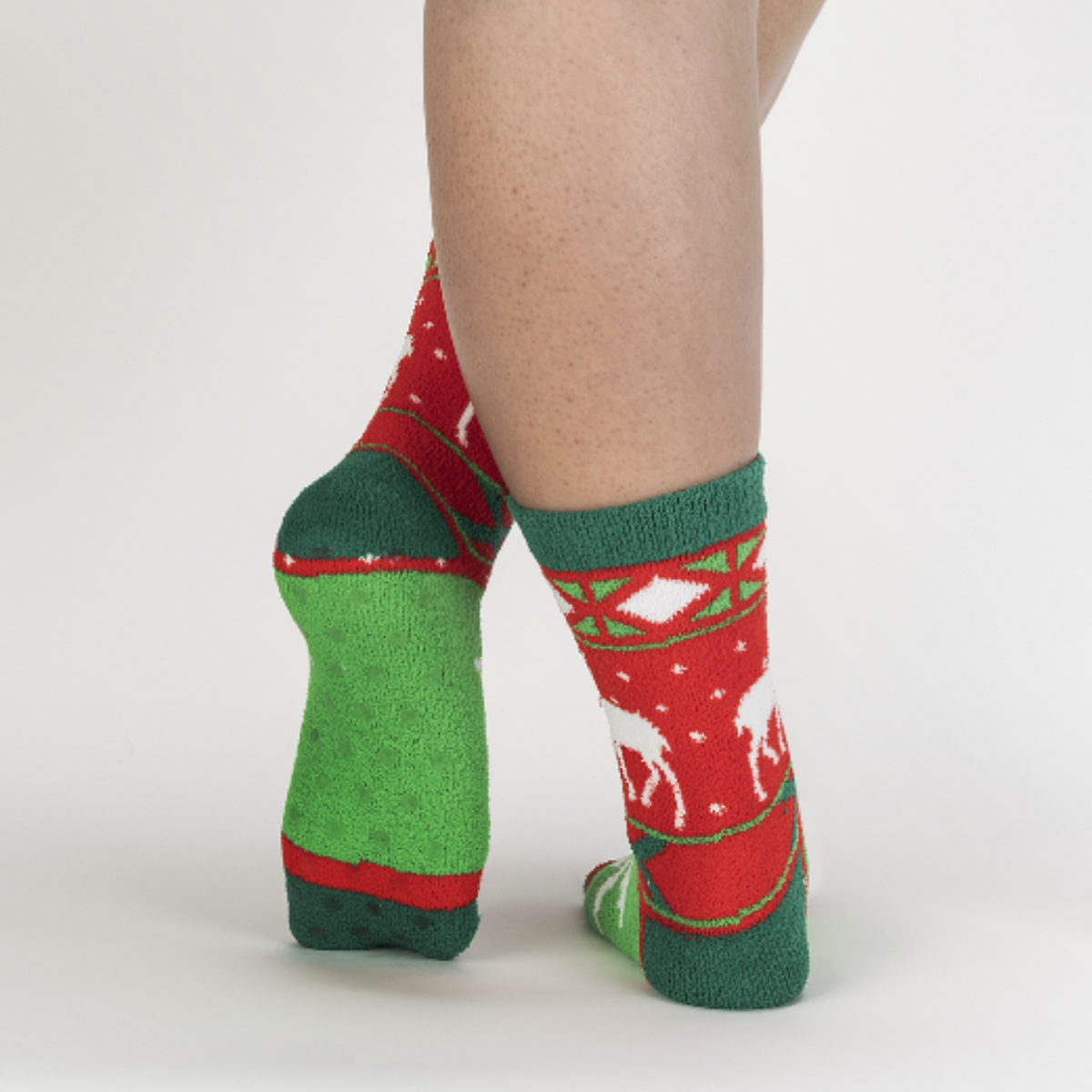 Sock It To Me Happy Holidays, My Deer women&#39;s slipper sock featuring red and green fair isle pattern with stag. Slipper socks shown on model from behind showing bottom of slipper sock.. 