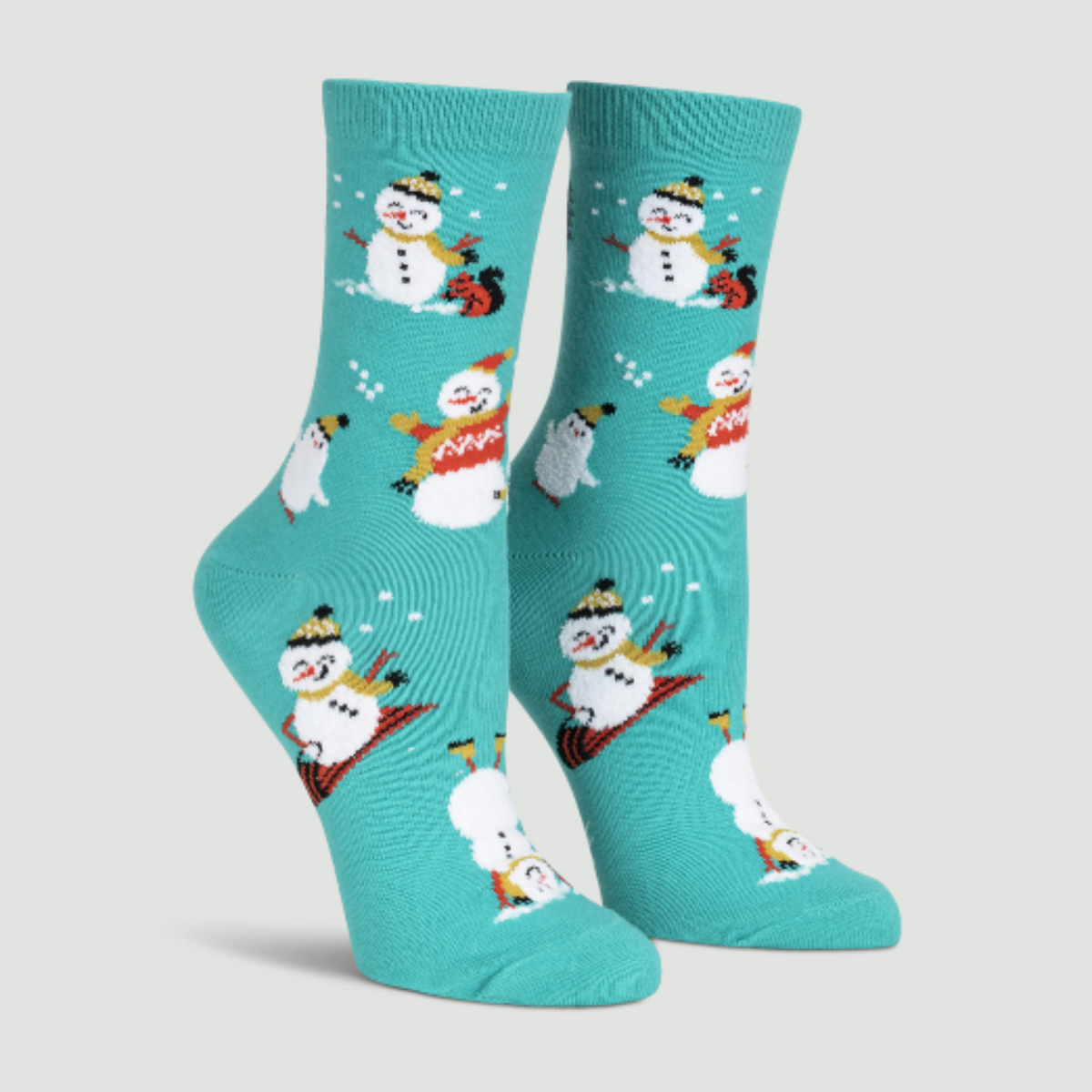 Sock It To Me Having Snow Much Fun women&#39;s crew sock featuring teal sock with smiling snowmen and white cat all over. Shown on display feet. 