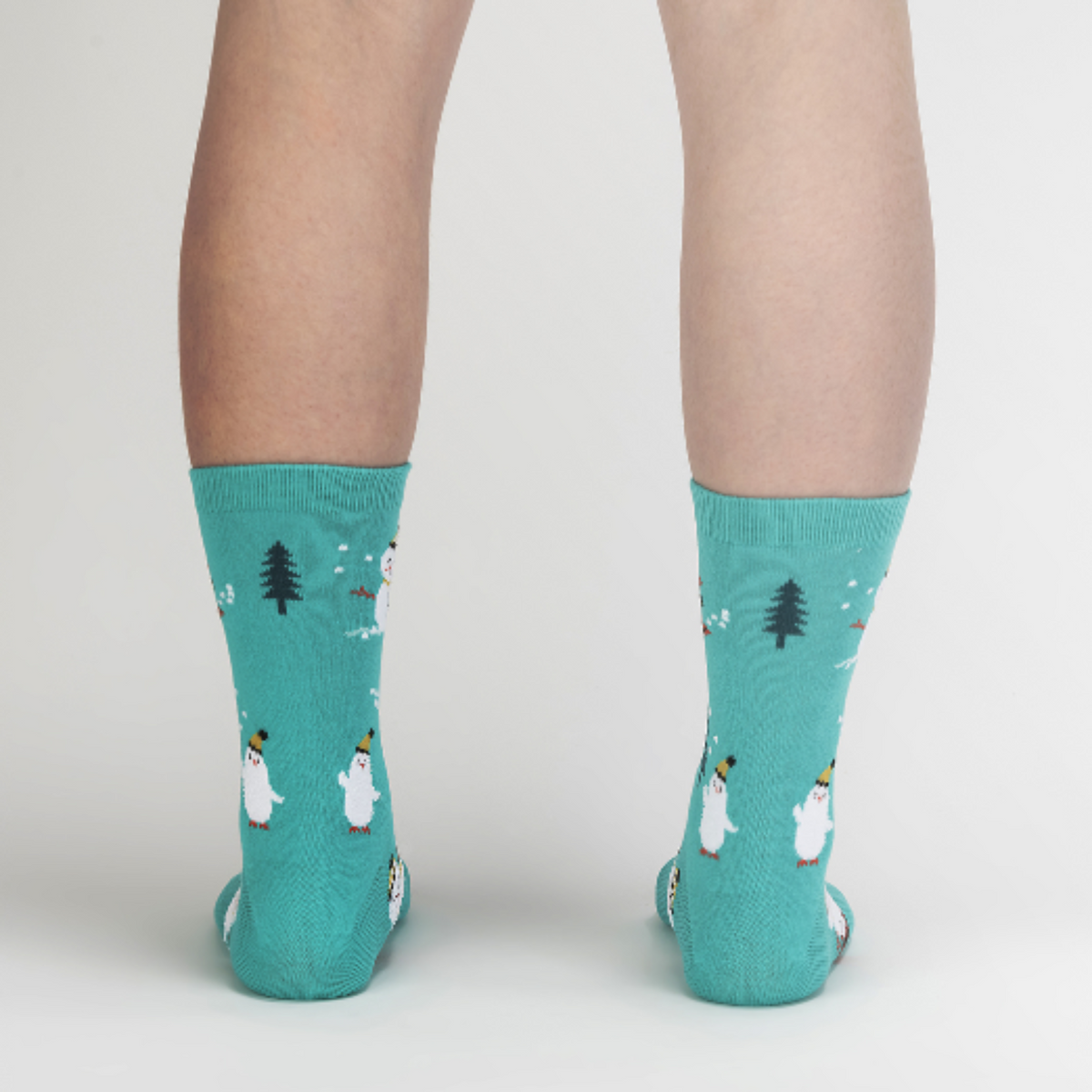Sock It To Me Having Snow Much Fun women&#39;s crew sock featuring teal sock with smiling snowmen and white cat all over. Shown on model from behind.