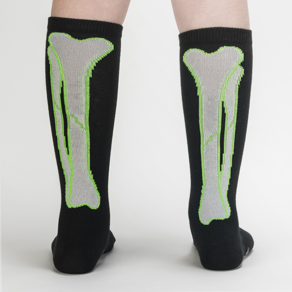 Sock It To Me It&#39;s Going Tibia Good Day kids&#39; sock (GLOW IN THE DARK!) featuring a black knee high sock with outline of tibia bones worn by model from back