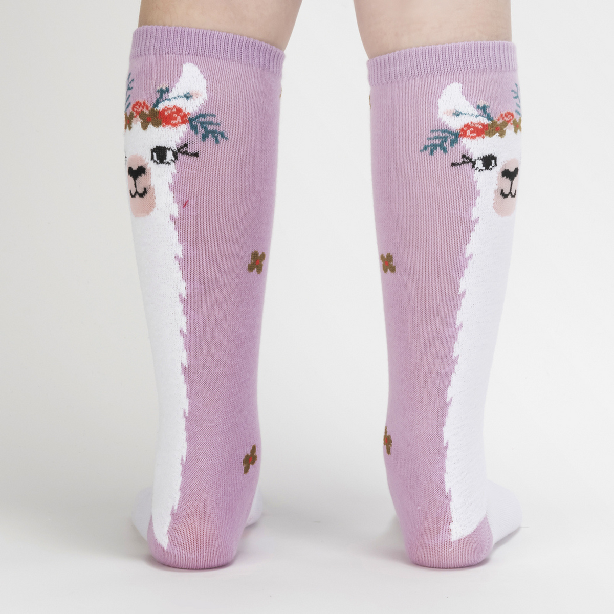 Sock It To Me Llama Queen kids&#39; sock featuring purple knee high sock with white llama wearing a floral crown worn by model seen from back