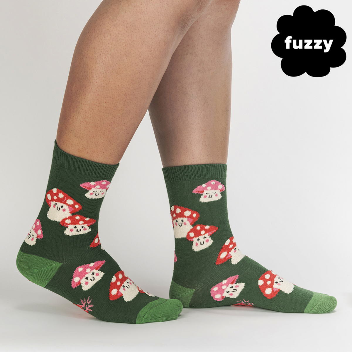 Sock It To Me Mellow Mushrooms women&#39;s sock featuring a green crew sock with red capped smiling mushrooms all over worn by a model from side