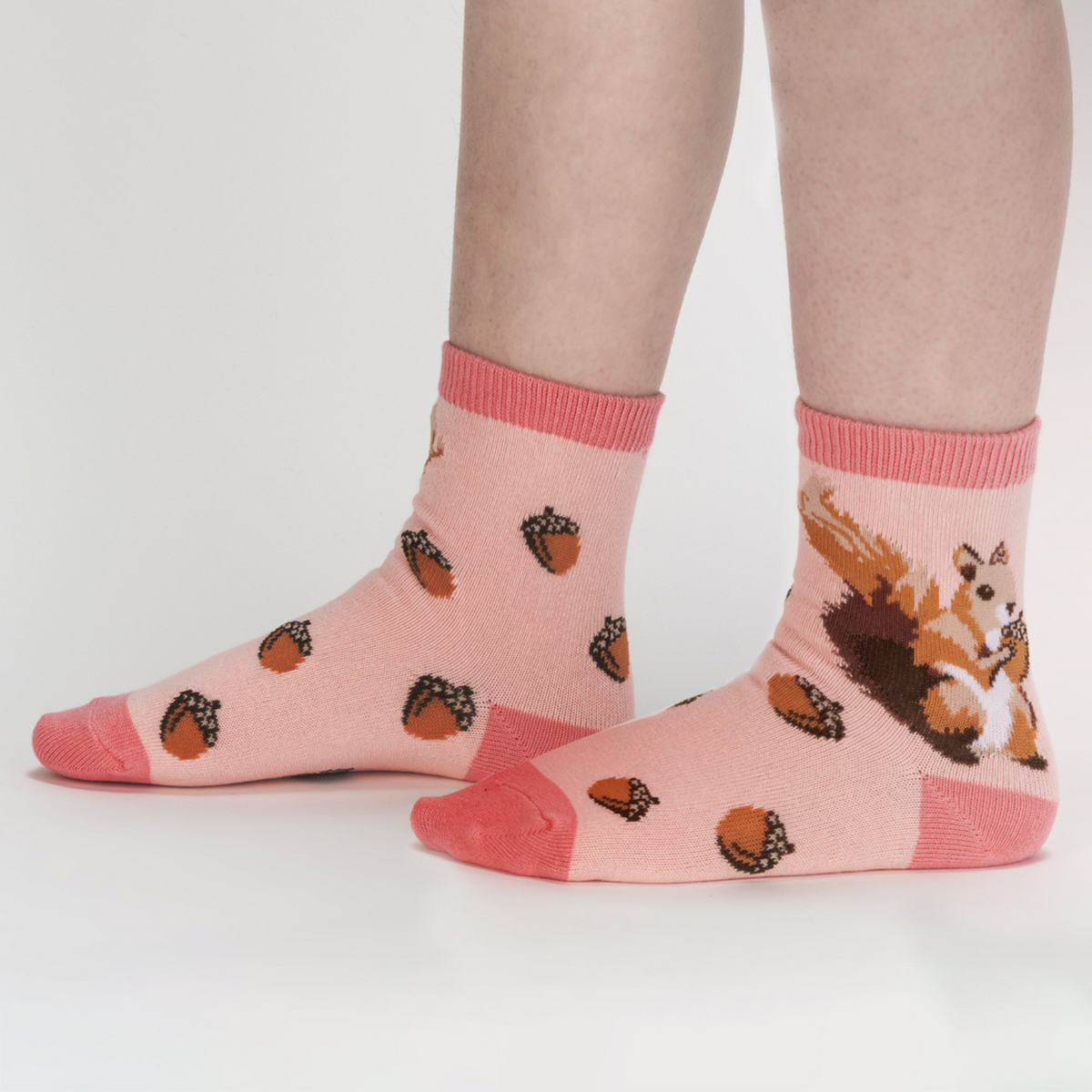 Sock It To Me My Dear Hedgehog 3-pack kids&#39; socks featuring peach sock with acorns all over and squirrel at ankle worn by model from side