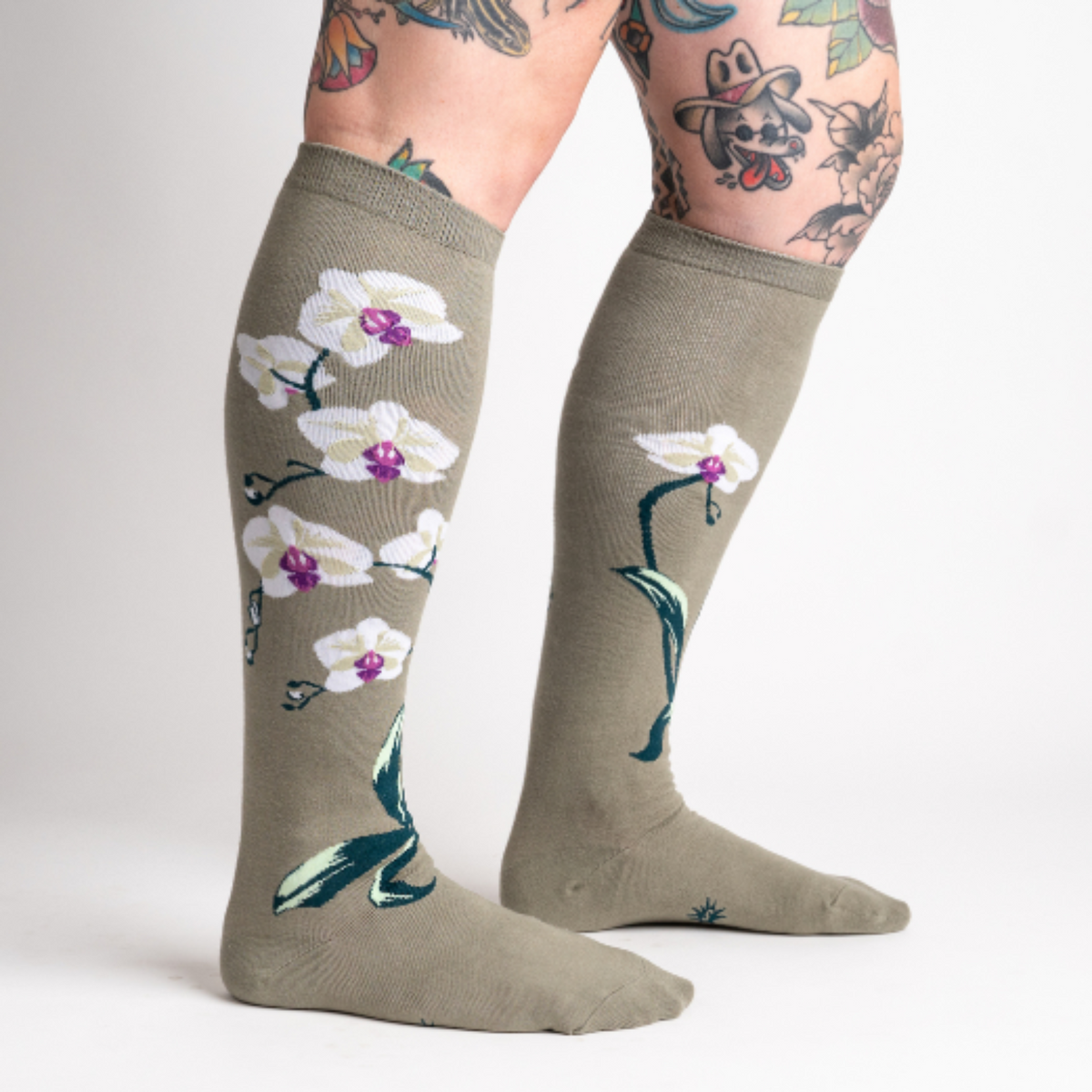 Sock It To Me Orchids women&#39;s knee high sock featuring beige sock with white orchid the length of the sock. Shown on model from side. 
