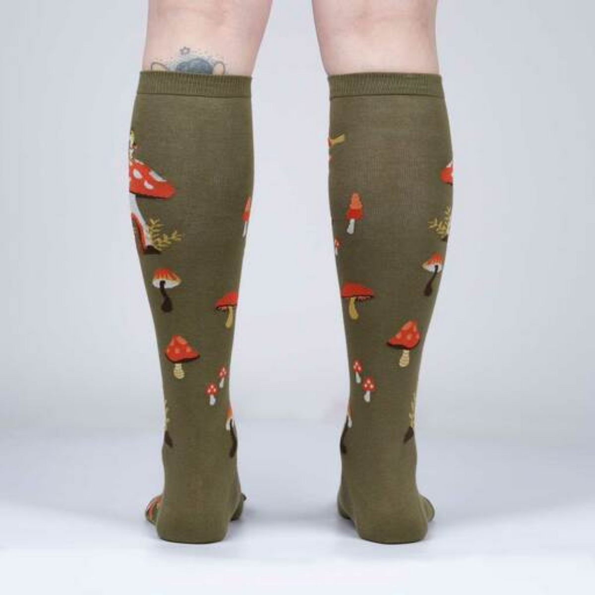 Women&#39;s Sock It To Me Shroom and Board women&#39;s and kids&#39; sock featuring green knee high with deer, squirrel, and mushrooms all over on model from behind