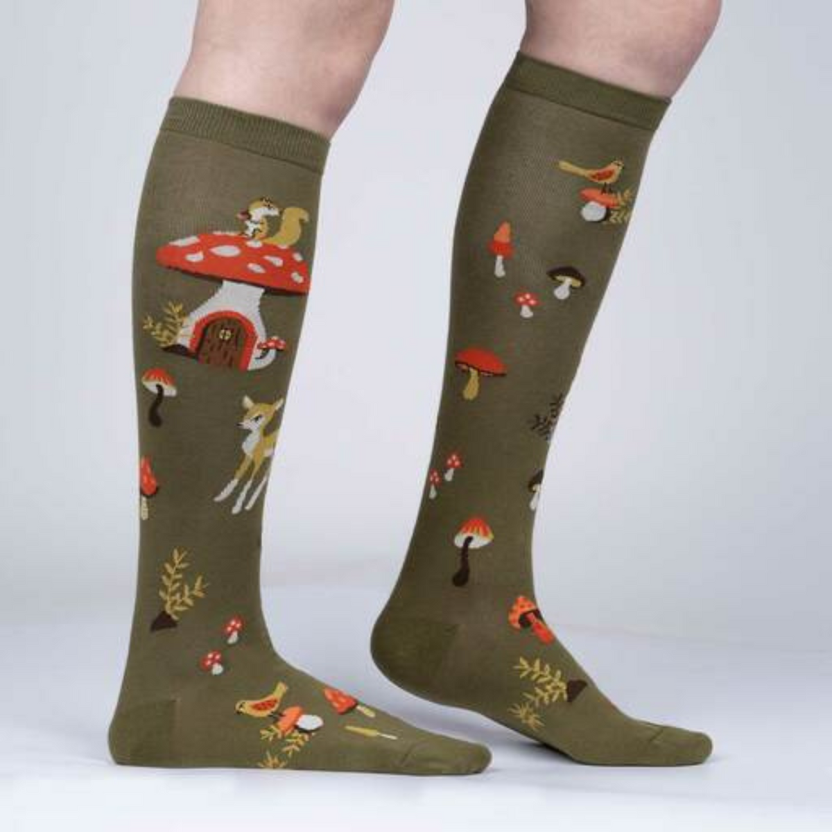 Women&#39;s Sock It To Me Shroom and Board women&#39;s and kids&#39; sock featuring green knee high with deer, squirrel, and mushrooms all over on model from side