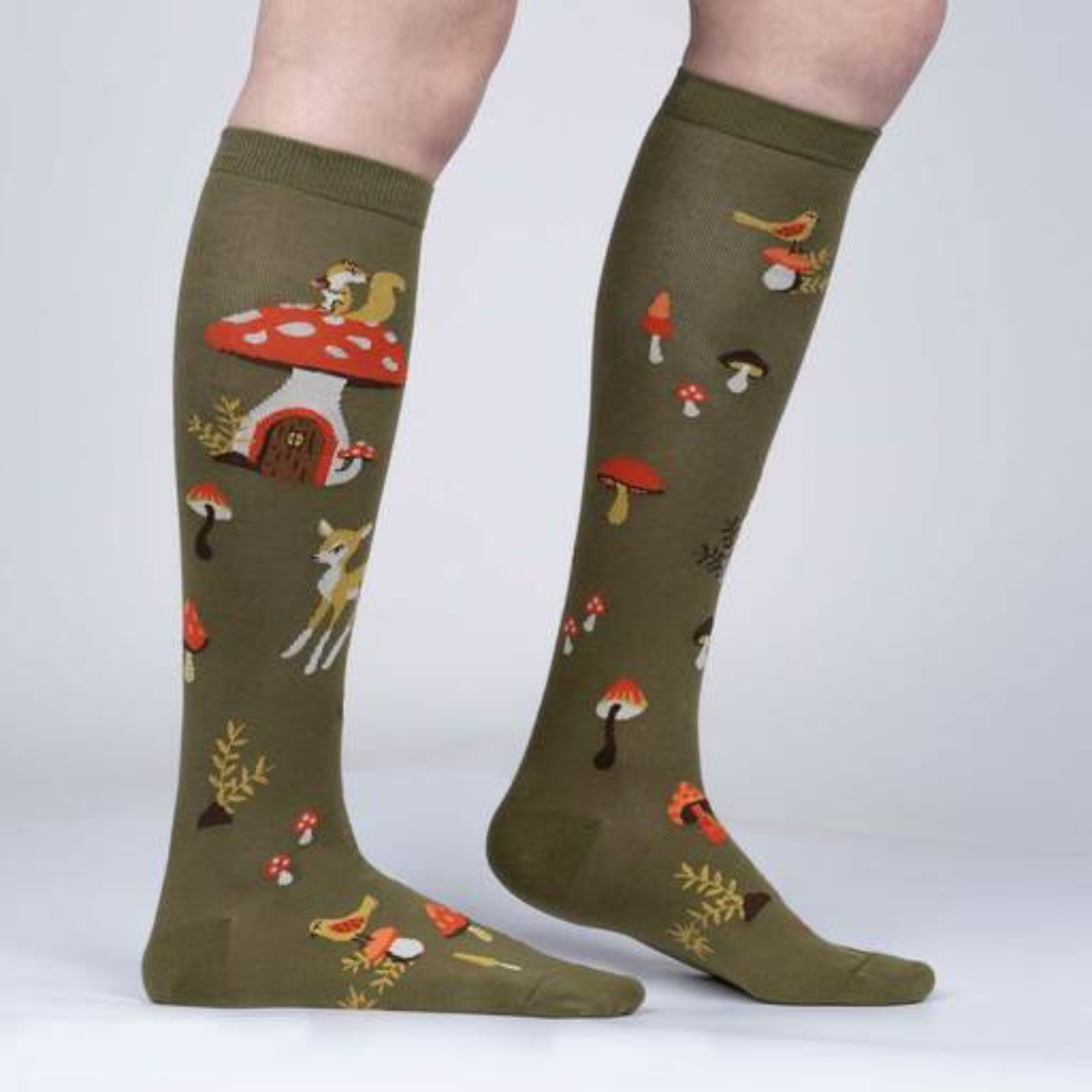 Women's Sock It To Me Shroom and Board women's and kids' sock featuring green knee high with deer, squirrel, and mushrooms all over on model from side