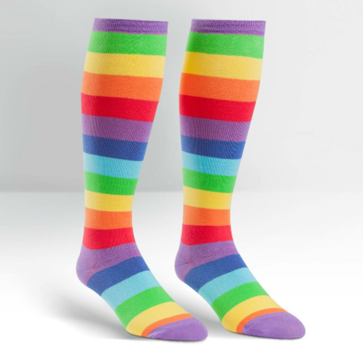 Sock It To Me Super Juicy extra-stretchy knee high socks featuring rainbow stripes all over. Socks shown on display feet from the side. 