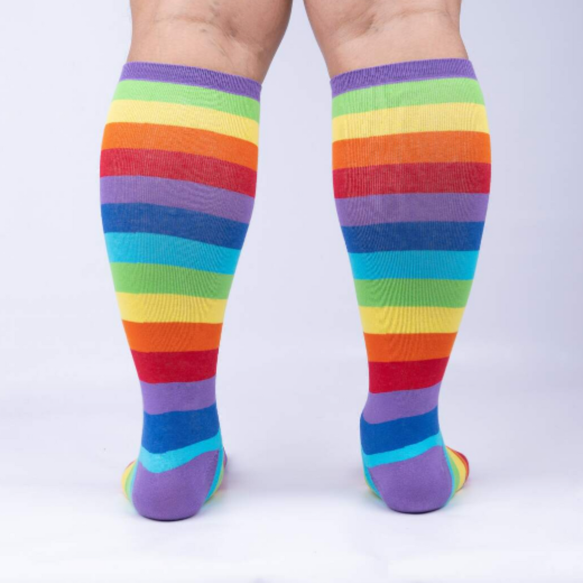 Sock It To Me Super Juicy extra-stretchy knee high socks featuring rainbow stripes all over. Socks shown on model from behind.