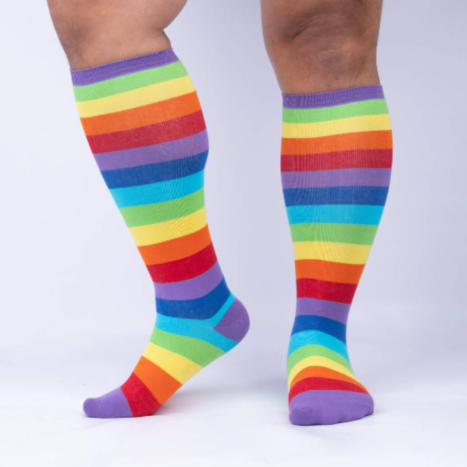 Sock It To Me Super Juicy extra-stretchy knee high socks featuring rainbow stripes all over. Socks shown on model from the side. 