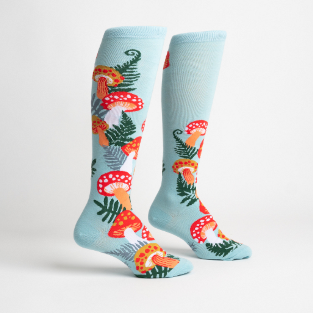 Sock It To Me Wonderland Mushrooms women&#39;s knee high sock featuring light blue sock with orange mushrooms and green ferns. Socks shown on display feet.. 