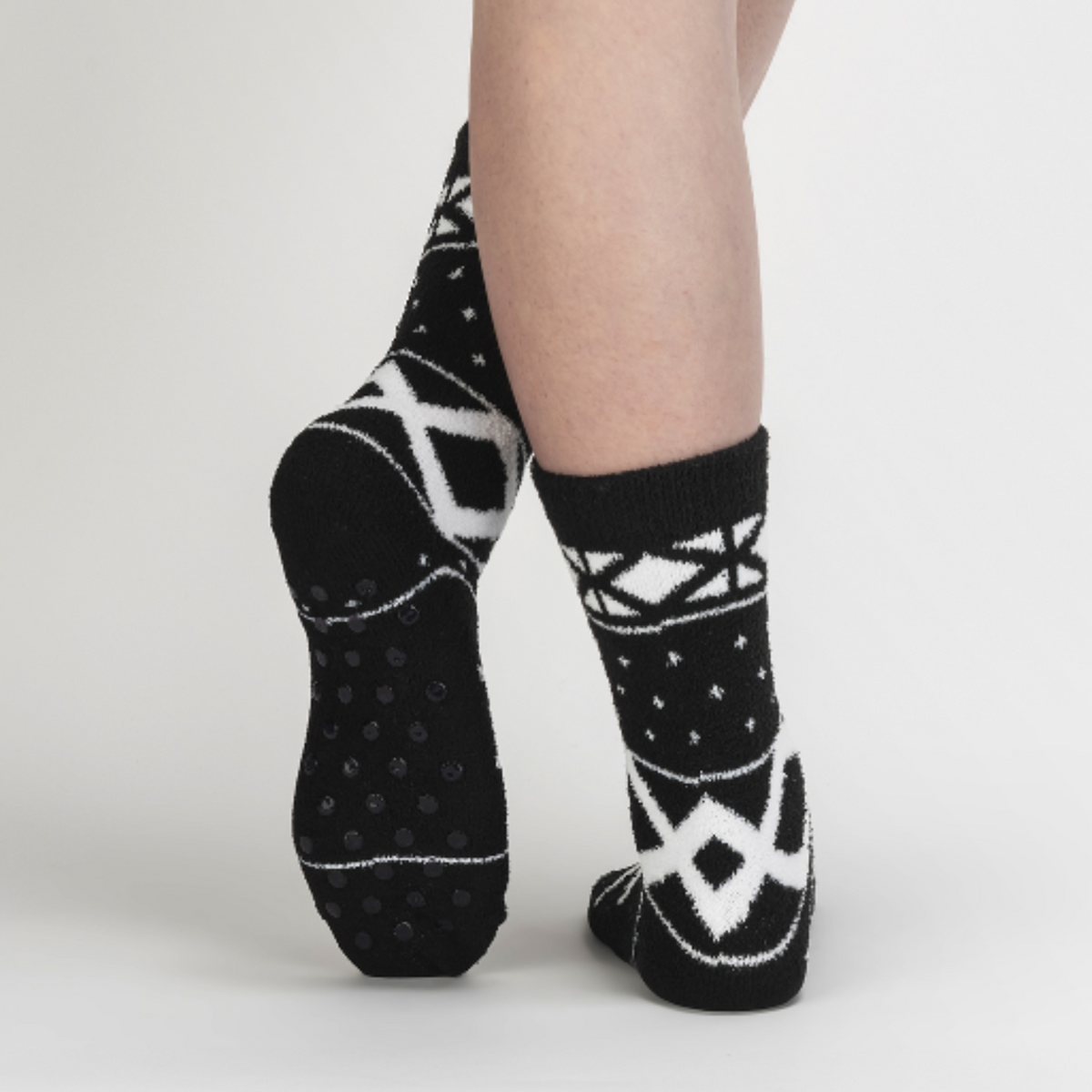 Sock It To Me You Sweater Believe It women&#39;s slipper sock featuring black fair isle pattern. Socks worn by model seen from behind showing bottom of sock.. 