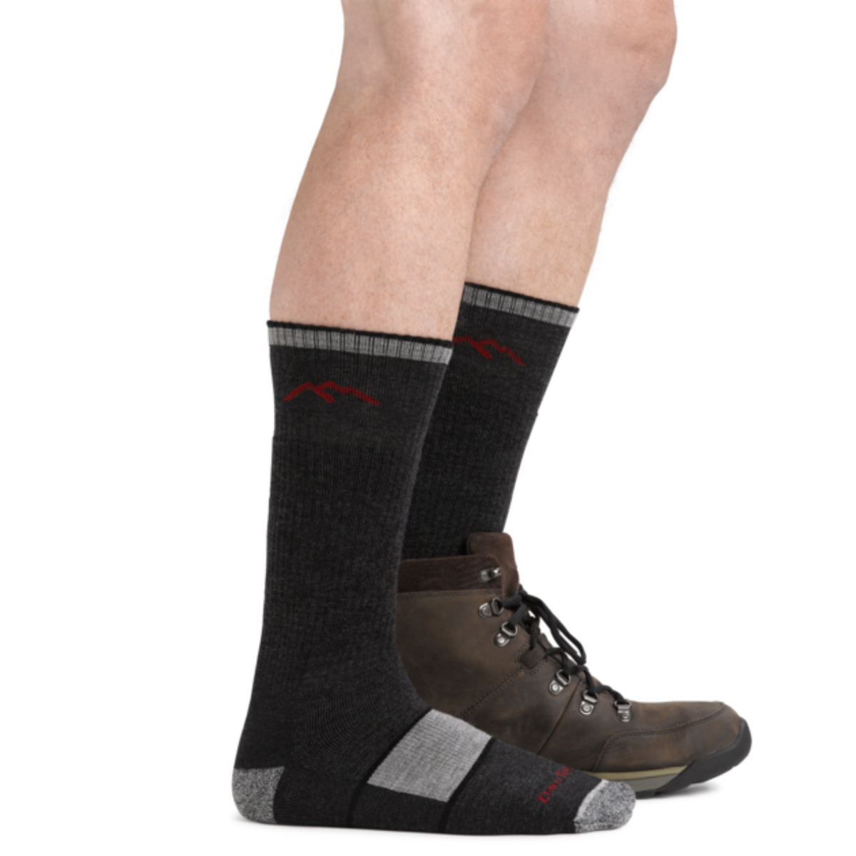 Darn Tough 1405 Hiker Boot with Full Cushion Midweight Men&#39;s crew Sock in black. Socks shown on model from side wearing one hiking boot. 