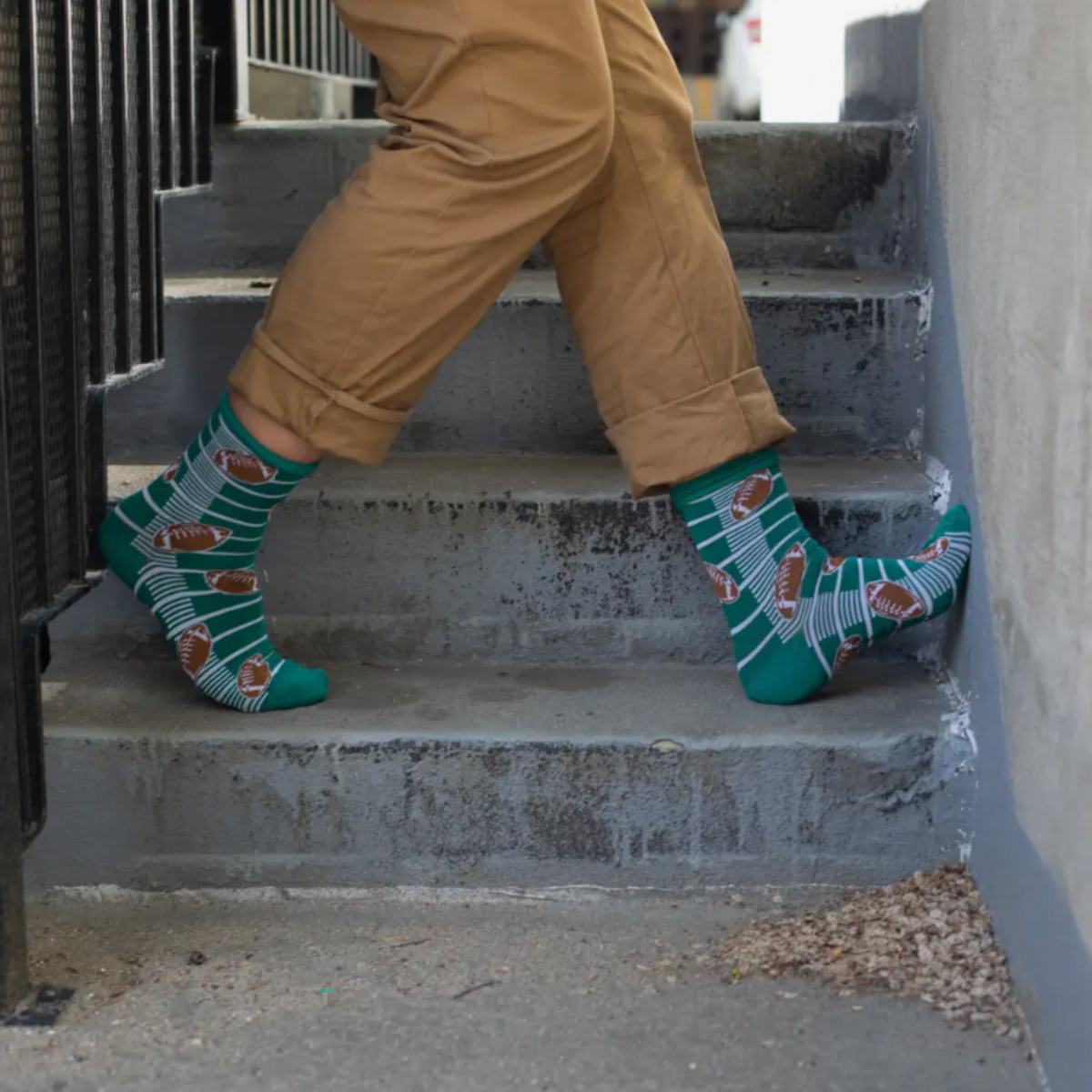 Good Luck Sock Football men&#39;s sock featuring green field with yardlines and footballs worn by model