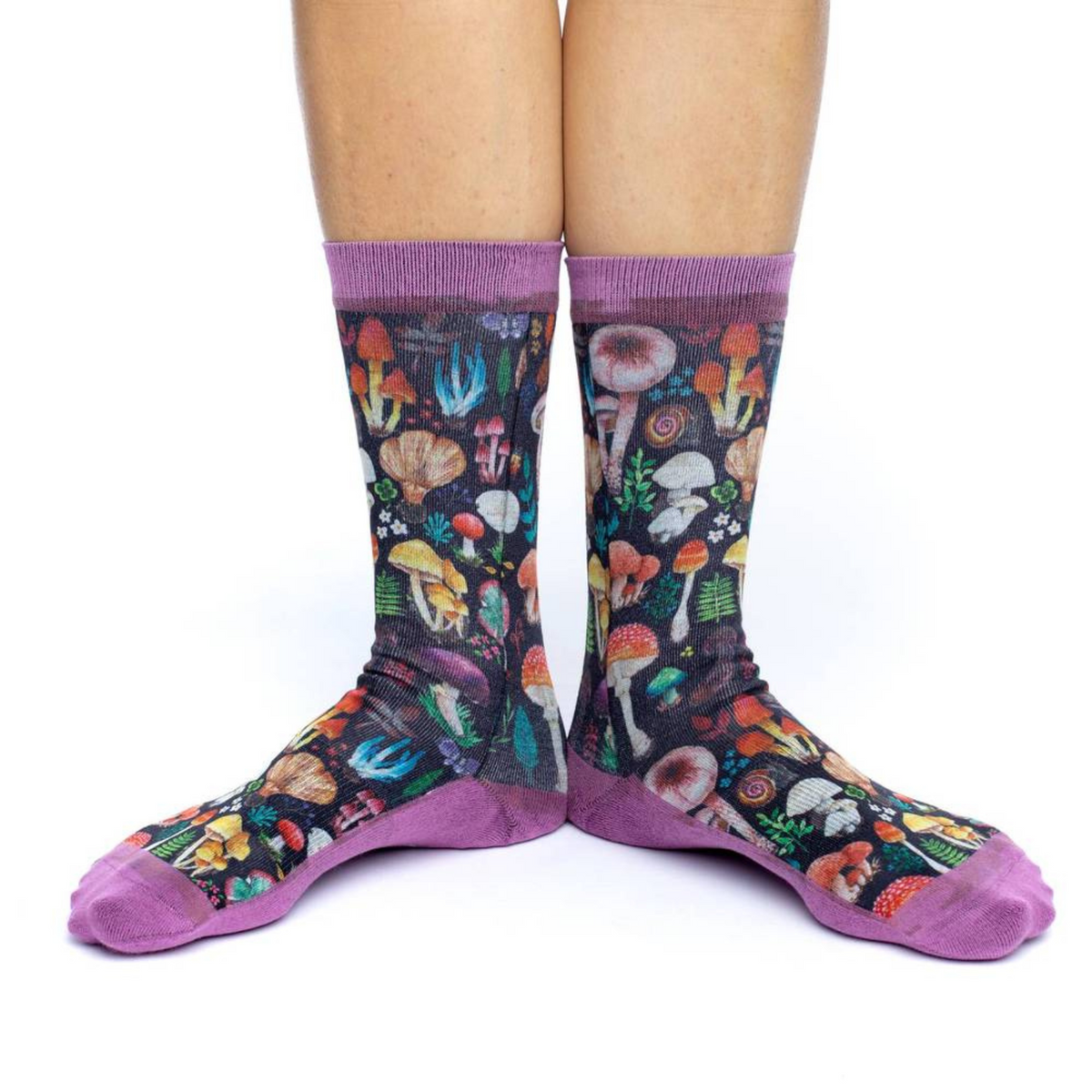 Good Luck Sock Mushroom women&#39;s socks featuring different types of mushrooms on black background on display with pink cuff, heel and toe on model