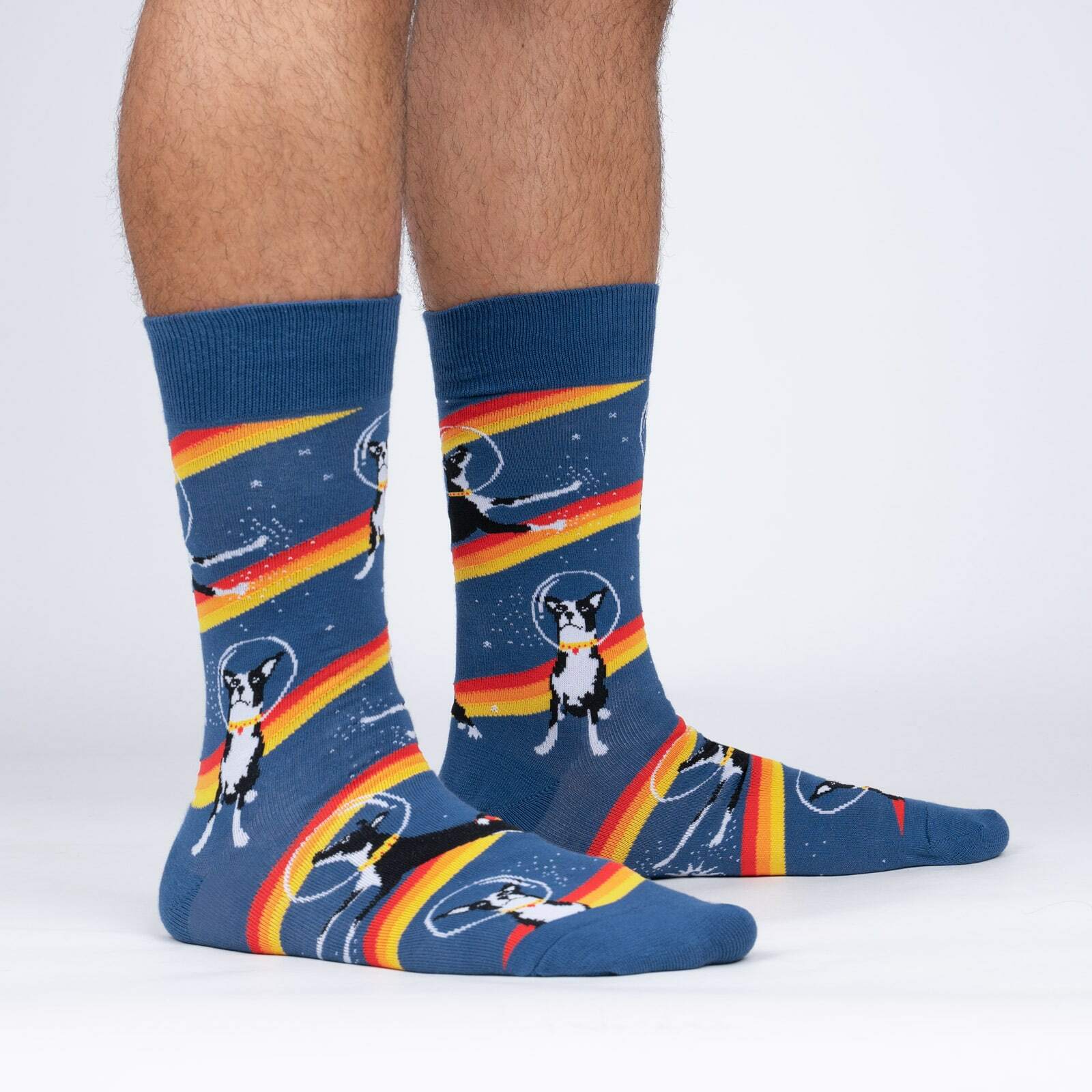 Sock It To Me Astro Puppy men's crew sock featuring blue sock with orange, red, and yellow stripes all over and dog in astronaut helmet. Socks worn by model seen from the side. 