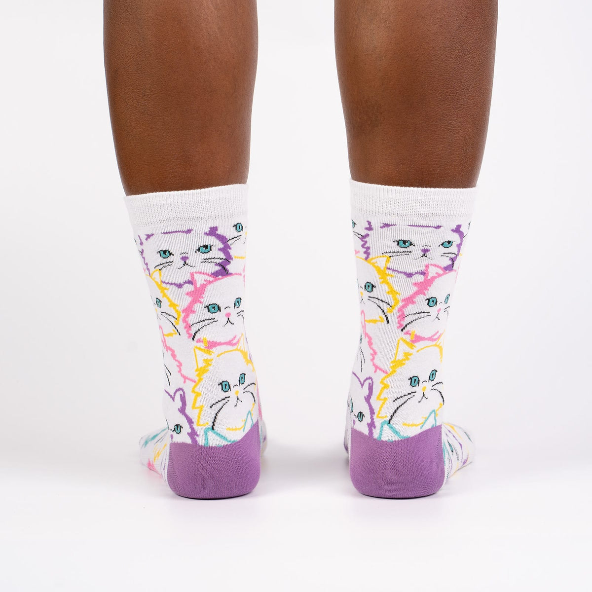 Sock It To Me Fur Real women&#39;s crew sock featuring white sock with lavender heel and toe with white cats outlined in pastel colors. Socks worn by model seen from behind.
