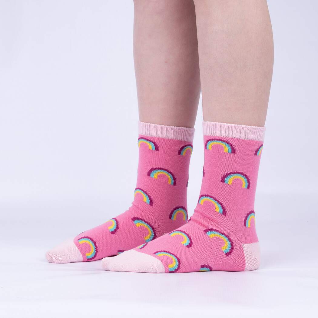 Sock It To Me Look At Me Meow 3-pack kids&#39; socks featuring pink socks with rainbows all over worn by model seen from the side