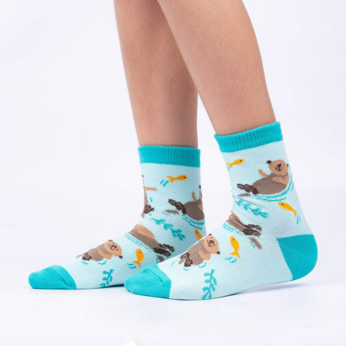 Sock It To Me My Otter Half 3-pack kids&#39; socks featuring light blue socks with otters swimming with goldfish worn by model seen from the side