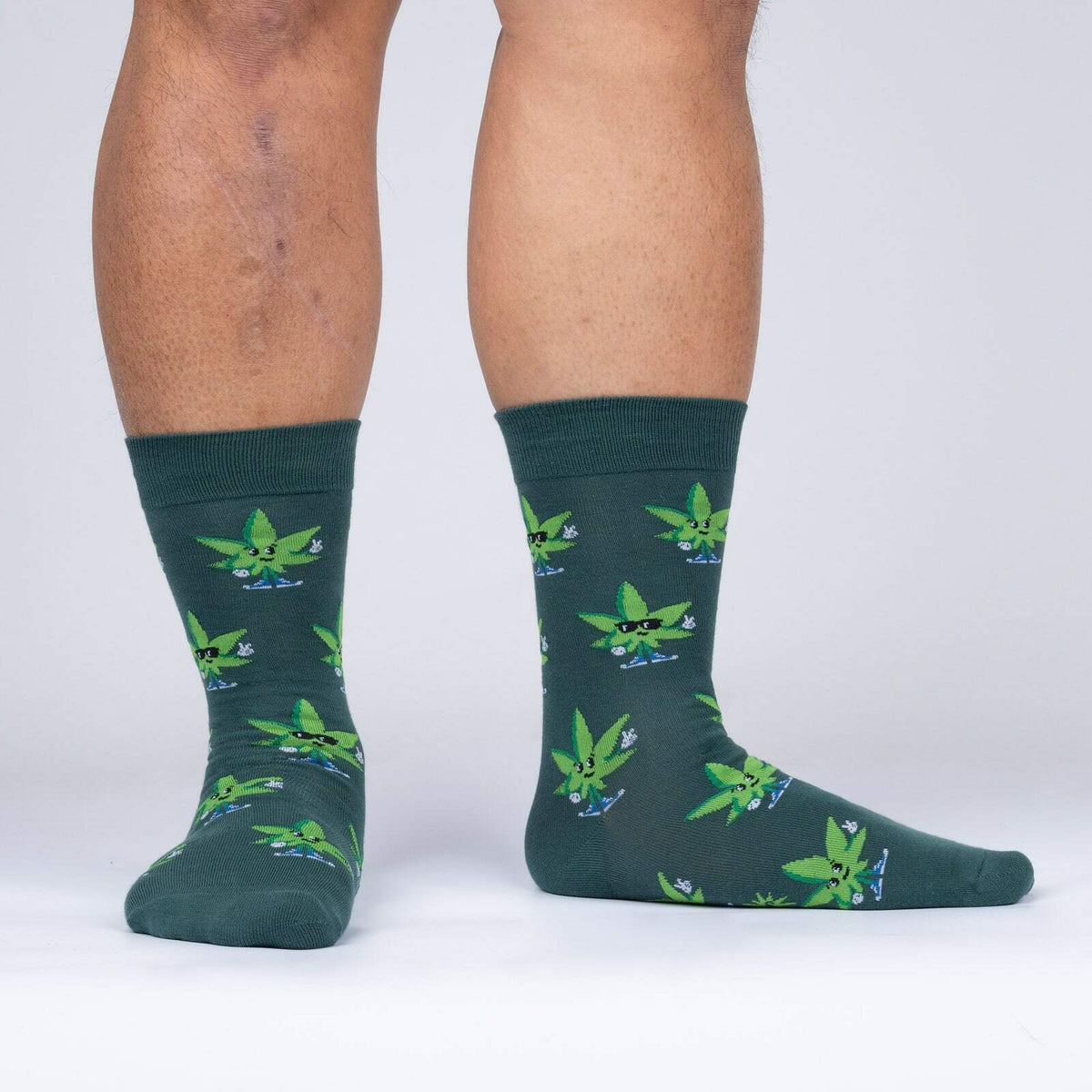 Sock It To Me Peace Out men&#39;s sock featuring green sock with cannabis leaves worn by model shown from side