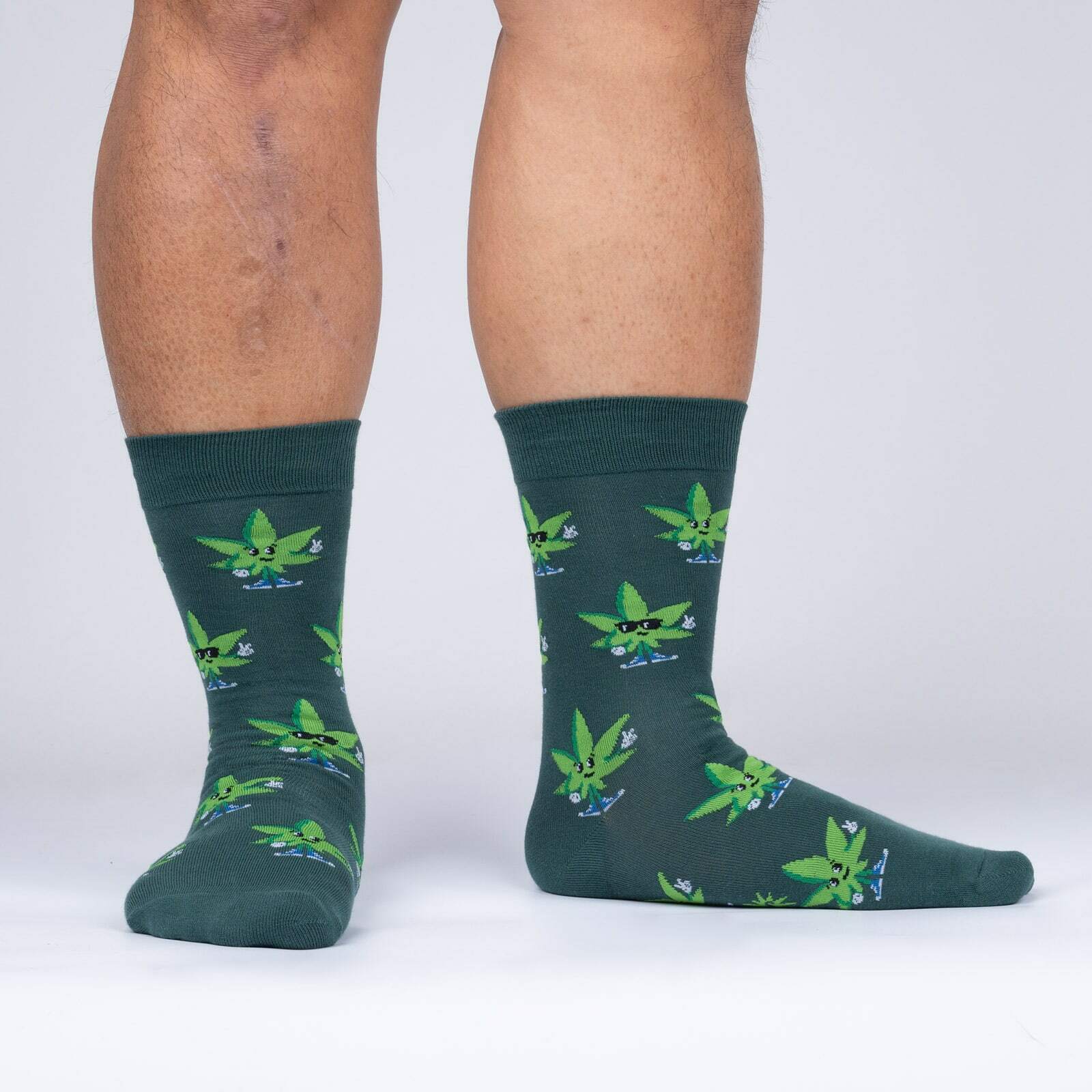 Sock It To Me Peace Out men's sock featuring green sock with cannabis leaves worn by model shown from side