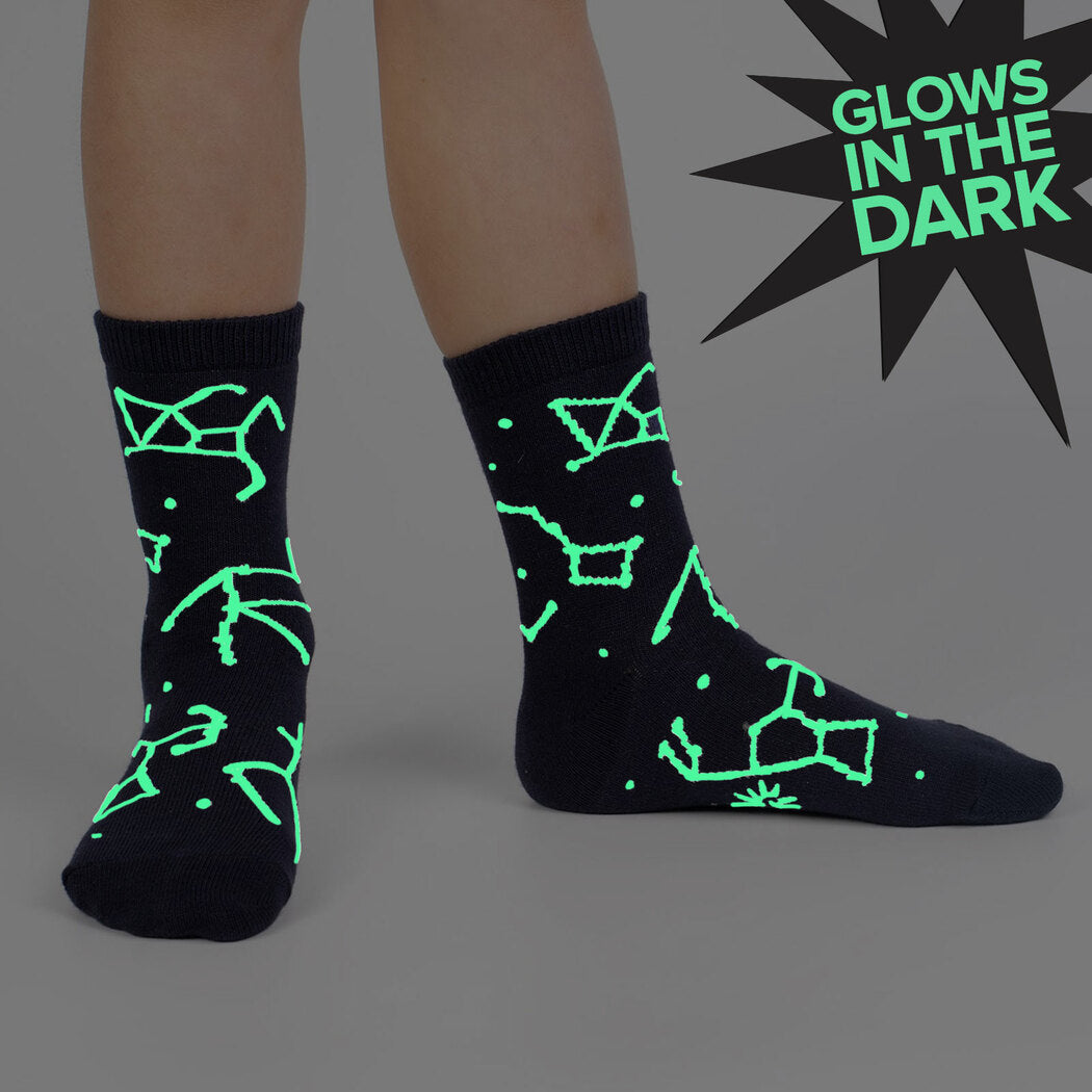 Sock It To Me Solar System (GLOWS IN THE DARK!) 3-pack kids&#39; socks featuring navy blue socks with constellations all over that glow worn by model seen from the side