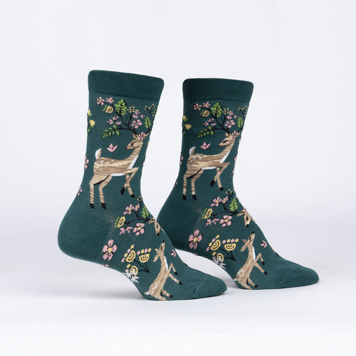 Sock It To Me Spring Awakening women's crew sock. Featuring green sock with deer and spring flowers. Socks shown on display feet. 