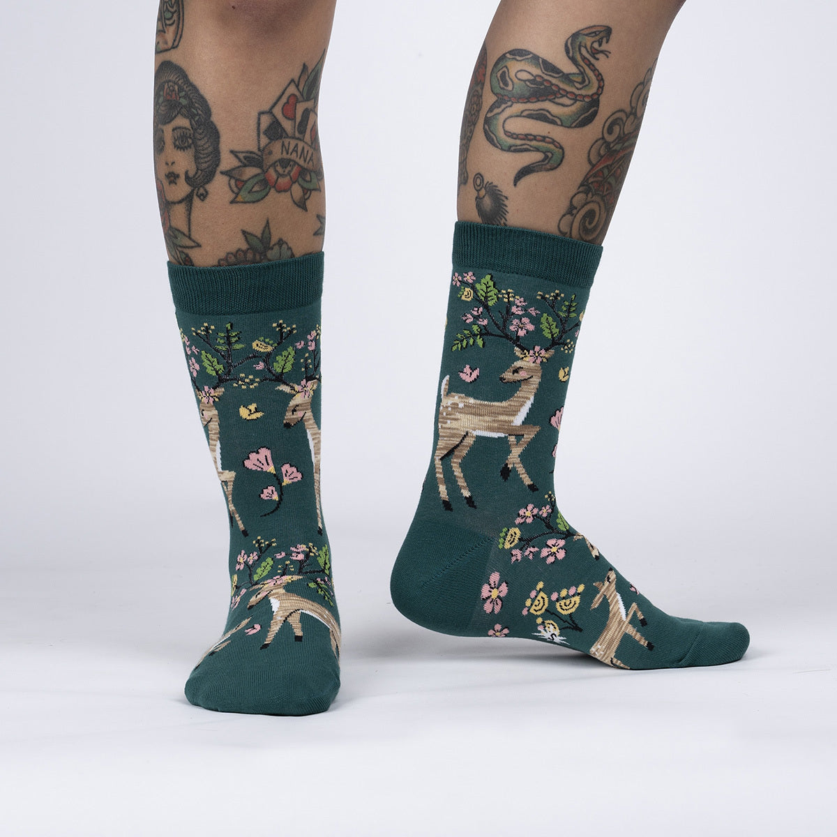 Sock It To Me Spring Awakening women&#39;s crew sock. Featuring green sock with deer and spring flowers. Socks shown on model.