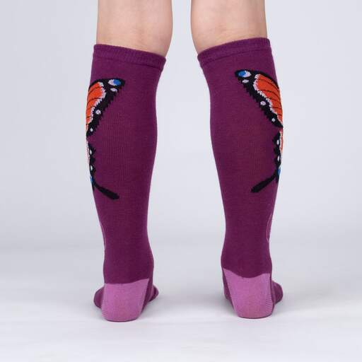 Sock It To Me The Monarch women&#39;s, kids&#39;, and extra-stretchy socks on model from side. Socks are purple featuring monarch butterfly. Shown on youth model from behind.. 