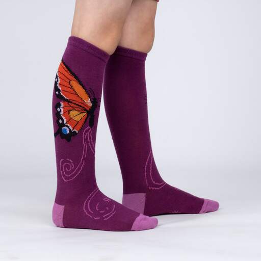 Sock It To Me The Monarch women&#39;s, kids&#39;, and extra-stretchy socks on model from side. Socks are purple featuring monarch butterfly. Shown on youth model from side. 