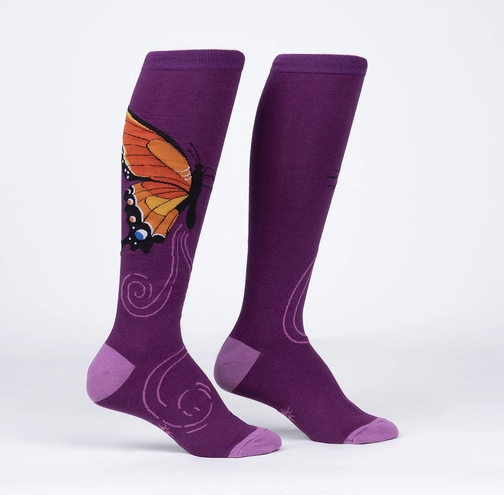 Sock It To Me The Monarch women&#39;s, kids&#39;, and extra-stretchy socks on model from side. Socks are purple featuring monarch butterfly. Shown on display feet.  