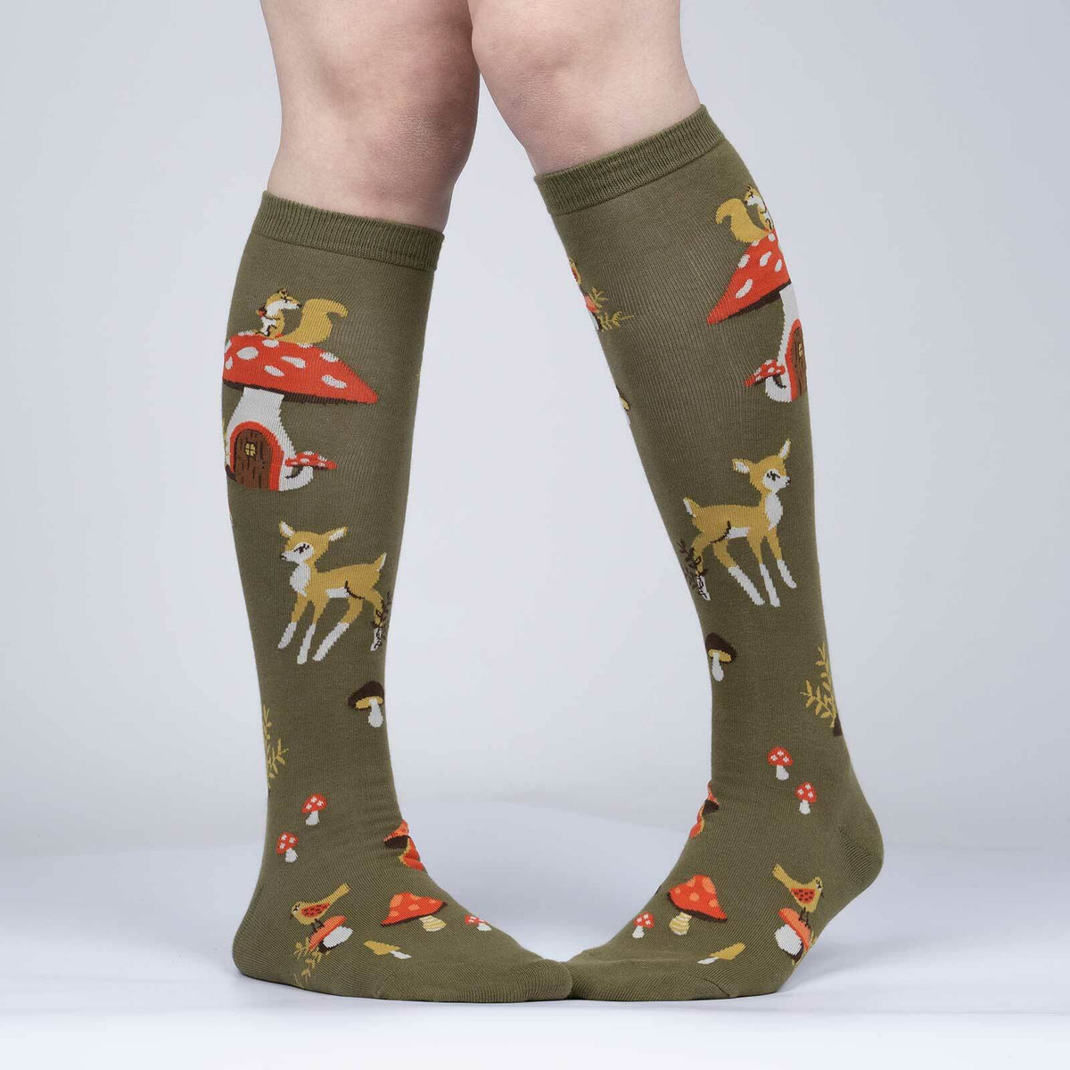 Women&#39;s Sock It To Me Shroom and Board women&#39;s and kids&#39; sock featuring green knee high with deer, squirrel, and mushrooms all over worn by model seen from front